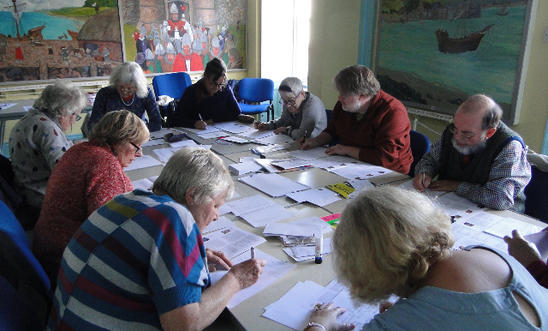 People sitting round a table writing letters People sitting round a table writing letters